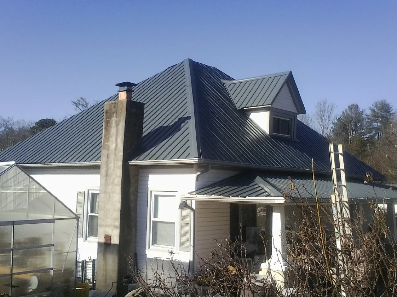 Dark blue standing seam metal roof on a white farmhouse with dormer — Slate & Tile Roof Repair by Roofing Brothers in Vickery