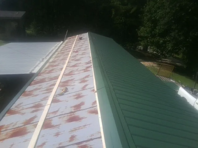 Old rusted panels beside newly installed green metal roofing — Wind Damage Roof Repair by Roofing Brothers in Vickery