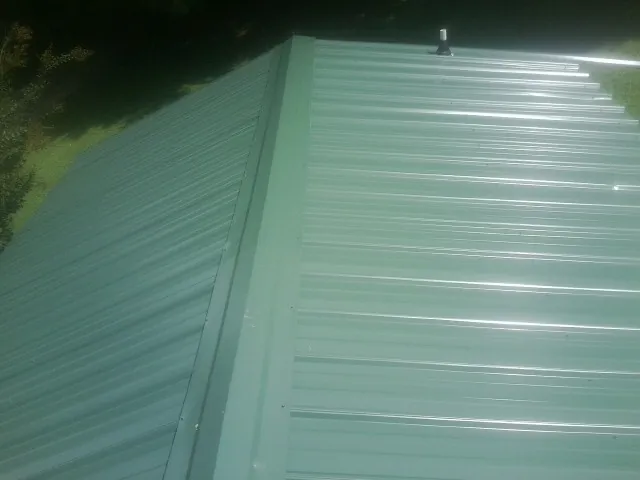 New green metal panels meeting at the ridge of a roof — Flat Roof Repair work by our crew in Vickery