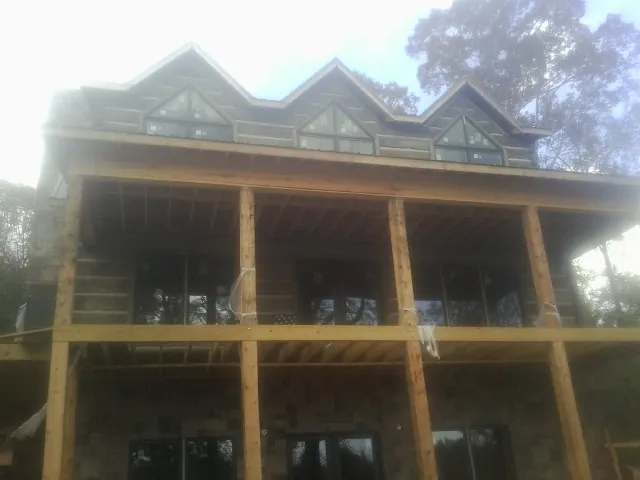 Dormers and porch framing on a large log home under construction — Roof Coating work by our crew in Vickery