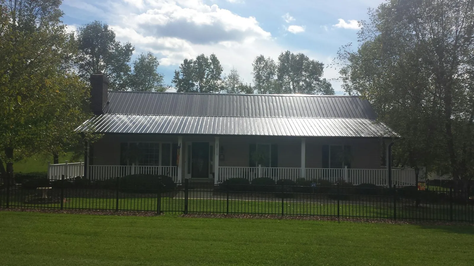 Gray metal roof on a brick ranch with a full width front porch — Gutter Guard Installation work by our crew in Vickery