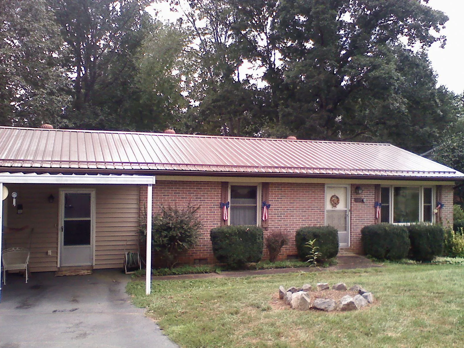 Bronze metal roof and carport on a brick ranch home — Roof Repair work by our crew in Vickery